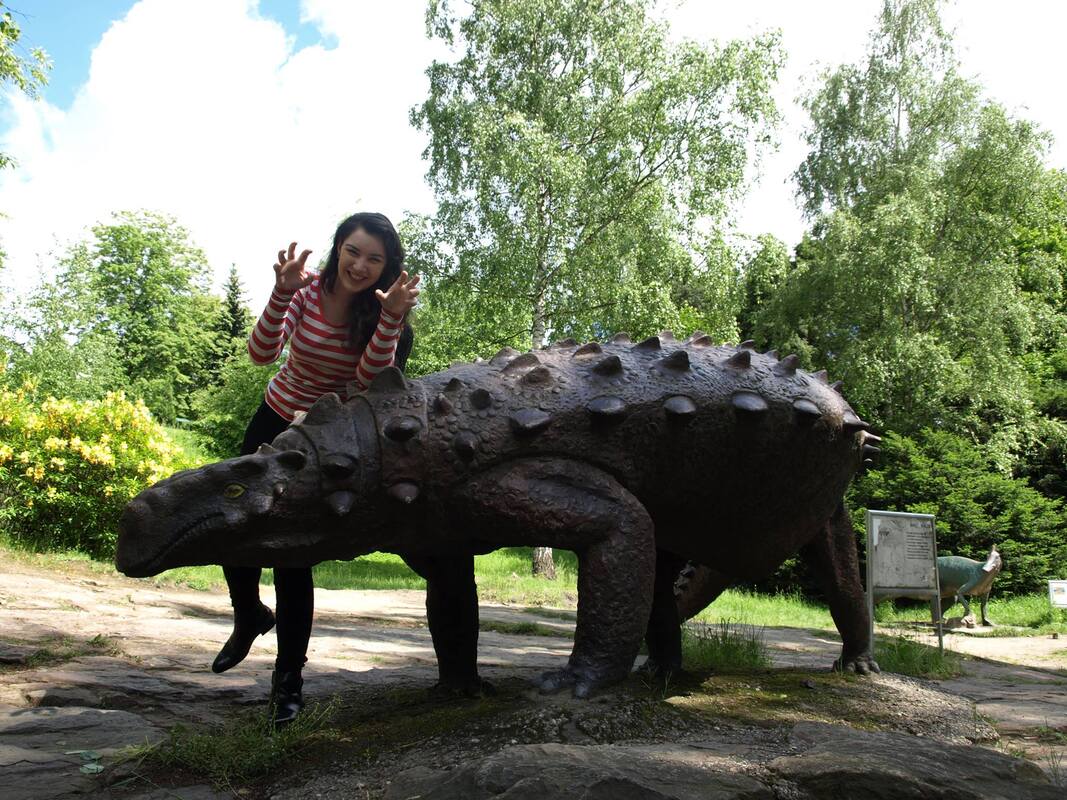 A picture of Tiffany Horan with a dinosaur sculpture, in Chorzów, Poland.